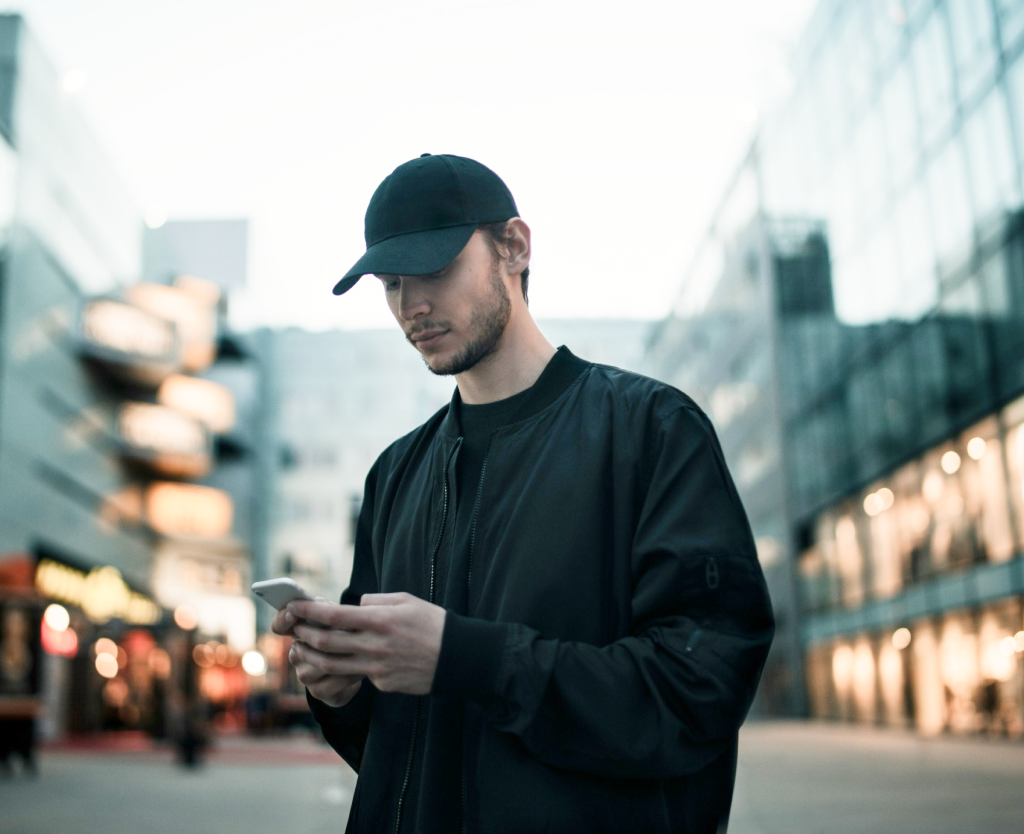 Man Wearing Hat Using Phone In Middle Of City